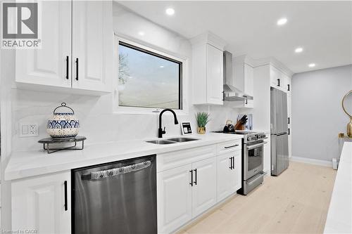 Kitchen with appliances with stainless steel finishes, wall chimney range hood, white cabinetry, light stone counters, and recessed lighting - 19 Broad Street, Brantford, ON - Indoor Photo Showing Kitchen With Stainless Steel Kitchen With Double Sink With Upgraded Kitchen