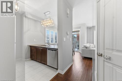 Kitchen featuring dishwasher, dark wood finish cabinets, light wood finished floors, and hanging lights - 4 Andruss Lane, Ancaster, ON - Indoor