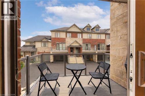 This property features a private balcony with glass railings, providing an open view of the surrounding townhomes - 4 Andruss Lane, Ancaster, ON - Outdoor