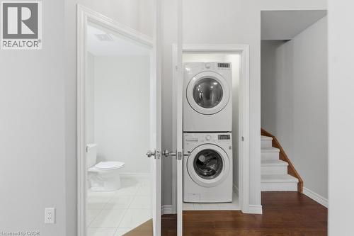 Laundry area with stacked washer and dryer and dark wood finished floors - 4 Andruss Lane, Ancaster, ON - Indoor Photo Showing Laundry Room