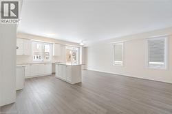 Kitchen with sink, light wood-type flooring, white cabinets, and a kitchen island - 