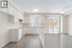 Kitchen with sink, white cabinetry, light stone countertops, light hardwood / wood-style floors, and a kitchen island - 