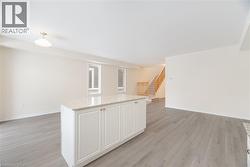 Kitchen featuring a center island, white cabinets, light stone counters, and light hardwood / wood-style flooring - 