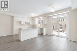 Kitchen with pendant lighting, light wood-type flooring, light stone counters, and white cabinets - 