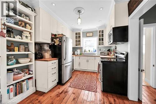 Kitchen with appliances with stainless steel finishes, white cabinetry, hanging light fixtures, ornamental molding, and light hardwood / wood-style flooring - 40 Locke Street S, Hamilton, ON - Indoor Photo Showing Kitchen