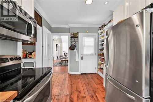 Kitchen with light hardwood / wood-style flooring, appliances with stainless steel finishes, ornamental molding, and white cabinetry - 40 Locke Street S, Hamilton, ON - Indoor Photo Showing Kitchen