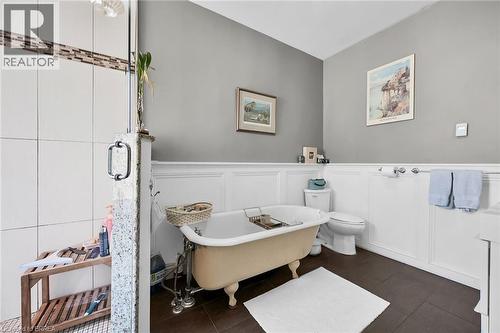 Bathroom featuring a tub to relax in, tile patterned floors, and toilet - 40 Locke Street S, Hamilton, ON - Indoor Photo Showing Bathroom