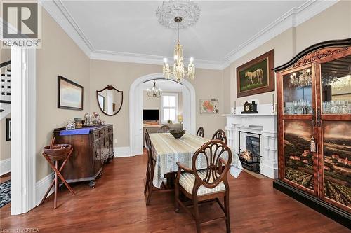 Dining area with dark wood-type flooring, a high end fireplace, crown molding, and a chandelier - 40 Locke Street S, Hamilton, ON - Indoor Photo Showing Dining Room