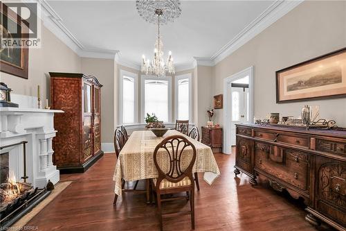 Dining space featuring dark hardwood / wood-style floors, crown molding, and a chandelier - 40 Locke Street S, Hamilton, ON - Indoor Photo Showing Dining Room With Fireplace