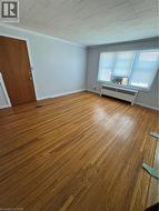 Spare room with ornamental molding, radiator, and wood finished floors - 