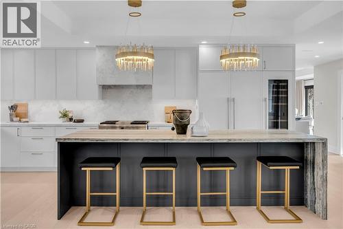 Two tone kitchen with light stone countertops, a kitchen breakfast bar, modern cabinets, a large island, and dual tone cabinetry - 841 Danforth Place, Burlington, ON - Indoor Photo Showing Kitchen With Upgraded Kitchen