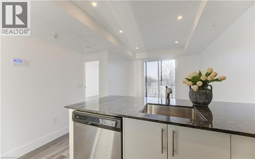 Kitchen featuring white cabinets, dishwasher, dark stone countertops, recessed lighting, and light wood-style flooring - 103 Roger Street Unit# 310, Waterloo, ON - Indoor Photo Showing Kitchen