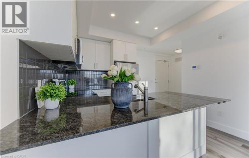 Kitchen featuring white cabinets, dark stone counters, a peninsula, recessed lighting, and black / electric stove - 103 Roger Street Unit# 310, Waterloo, ON - Indoor Photo Showing Kitchen With Upgraded Kitchen