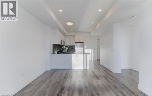 Kitchen featuring a tray ceiling, open floor plan, white cabinets, a peninsula, and backsplash - 103 Roger Street Unit# 310, Waterloo, ON - Indoor Photo Showing Kitchen