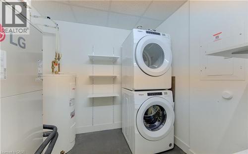 Laundry area with heating unit, water heater, and stacked washing machine and dryer - 103 Roger Street Unit# 310, Waterloo, ON - Indoor Photo Showing Laundry Room