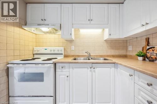 Kitchen featuring electric range, custom exhaust hood, white cabinetry, and light countertops - 66 Rodgers Road Unit# 2, Guelph, ON - Indoor Photo Showing Kitchen With Double Sink