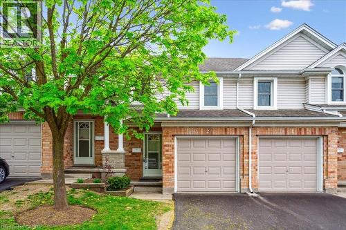 Townhome / multi-family property with driveway, a garage, a shingled roof, and brick siding - 66 Rodgers Road Unit# 2, Guelph, ON - Outdoor With Facade