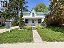 Charming white exterior with a green metal roof, featuring a covered front porch with white railings, a concrete walkway, and a manicured lawn - 101 John Street E, Wingham, ON  - Outdoor With Deck Patio Veranda 