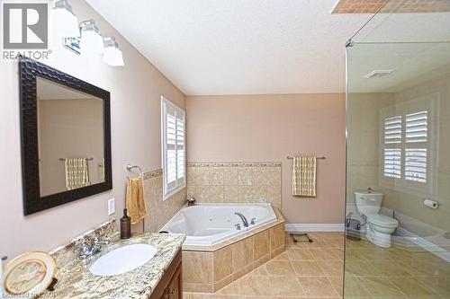 Bathroom with tile patterned flooring, vanity, tiled bath, a textured ceiling, and toilet - 34 Watervale Drive Unit# Upper, Kitchener, ON - Indoor Photo Showing Bathroom