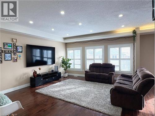 Living room with dark hardwood / wood-style flooring, a raised ceiling, and a textured ceiling - 34 Watervale Drive Unit# Upper, Kitchener, ON - Indoor Photo Showing Living Room