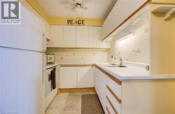 Kitchen with white appliances, white cabinets, light countertops, a ceiling fan, and backsplash - 