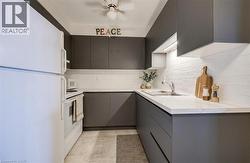 VIRTUALLY STAGED - Kitchen with white appliances, modern cabinets, a ceiling fan, and gray cabinets - 