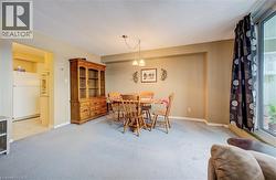 Dining area featuring plenty of natural light, light colored carpet, suspended lighting, and a textured ceiling - 