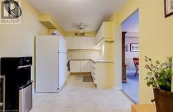 Kitchen featuring freestanding refrigerator, light flooring, a ceiling fan, light countertops, and white cabinets - 