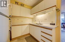 Kitchen with freestanding refrigerator, light countertops, white cabinetry, and backsplash - 