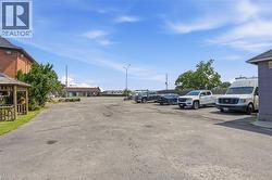 Asphalt parking lot featuring a brick building facade and a wooden gazebo - 
