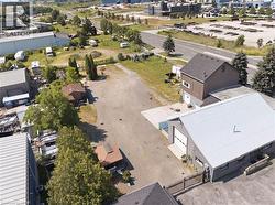 Expansive gravel lot surrounded by various commercial structures and mature trees - 