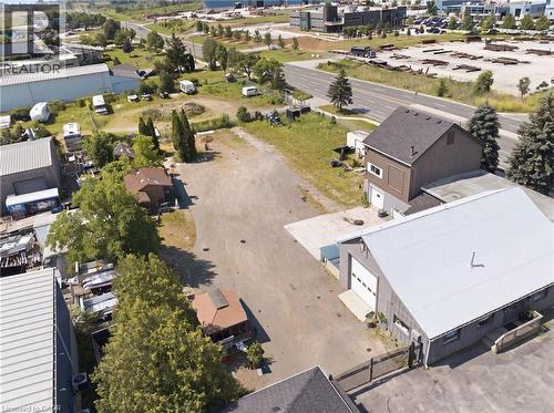 Expansive gravel lot surrounded by various commercial structures and mature trees - 1360 Rymal Road E, Hamilton, ON 