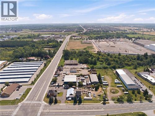 Aerial view showcasing expansive land parcels, multiple commercial buildings, and extensive paved roadways - 1360 Rymal Road E, Hamilton, ON 