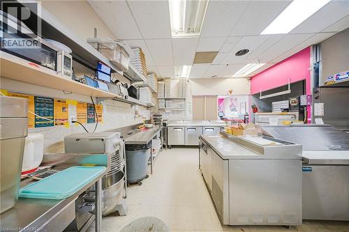 Kitchen featuring a drop ceiling, open shelves, light countertops, washer / dryer, and stainless steel microwave - 223 Louisa Street, Kitchener, ON 