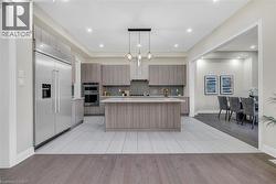 Kitchen featuring pendant lighting, appliances with stainless steel finishes, a center island with sink, modern cabinets, and light wood-type flooring - 