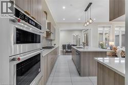 Kitchen featuring stainless steel appliances, modern cabinets, light stone countertops, pendant lighting, and recessed lighting - 
