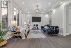 Living area featuring a glass covered fireplace, wood finished floors, and recessed lighting - 
