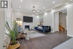 Living room with wood finished floors, a glass covered fireplace, recessed lighting, stairway, and a chandelier - 