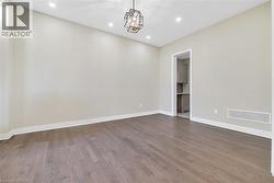 Spare room with dark wood-style flooring, recessed lighting, and a chandelier - 