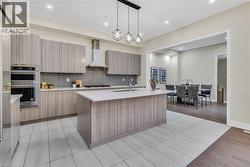 Kitchen with hanging light fixtures, light stone counters, tasteful backsplash, modern cabinets, and recessed lighting - 