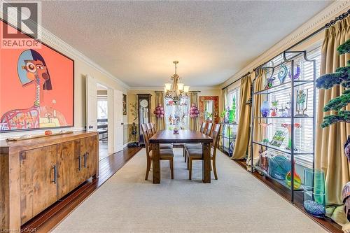 Dining space featuring suspended lighting, a textured ceiling, ornamental molding, dark wood-style flooring, and wainscoting - 4220 Millcroft Park Drive, Burlington, ON - Indoor