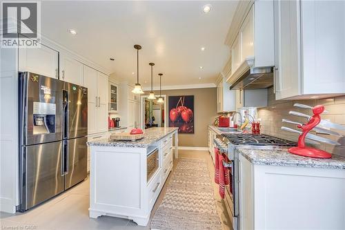 Kitchen featuring stainless steel appliances, white cabinetry, a center island, light stone countertops, and ornamental molding - 4220 Millcroft Park Drive, Burlington, ON - Indoor Photo Showing Kitchen With Upgraded Kitchen