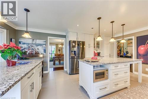 Kitchen featuring white cabinets, stainless steel appliances, light stone counters, decorative light fixtures, and glass insert cabinets - 4220 Millcroft Park Drive, Burlington, ON - Indoor Photo Showing Kitchen With Upgraded Kitchen