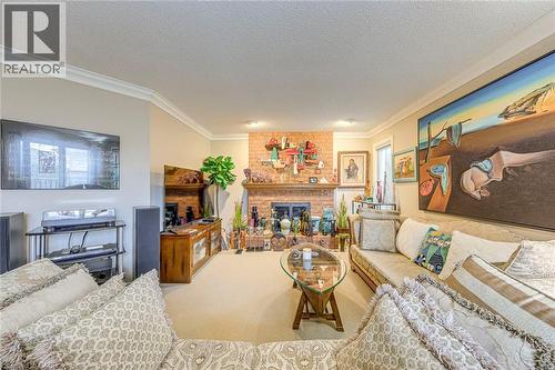 Living room featuring ornamental molding, a brick fireplace, carpet flooring, and a textured ceiling - 4220 Millcroft Park Drive, Burlington, ON - Indoor Photo Showing Living Room With Fireplace
