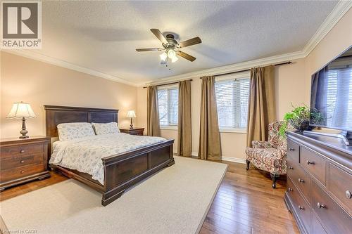 Bedroom featuring crown molding, light wood-style floors, a textured ceiling, and ceiling fan - 4220 Millcroft Park Drive, Burlington, ON - Indoor Photo Showing Bedroom