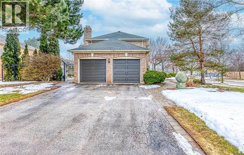 View of property exterior featuring asphalt driveway, a chimney, brick siding, a shingled roof, and a garage - 4220 Millcroft Park Drive, Burlington, ON - Outdoor