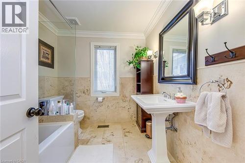 Bathroom with a wainscoted wall, crown molding, a garden tub, tile walls, and light tile patterned floors - 4220 Millcroft Park Drive, Burlington, ON - Indoor Photo Showing Bathroom