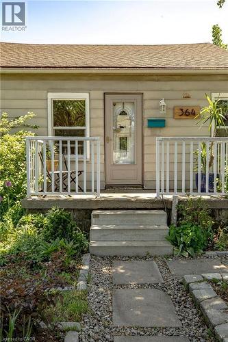 Front facade featuring horizontal siding, a light-colored entry door with decorative glass, and a small covered porch with white railing - 364 Tragina Avenue N, Hamilton, ON - Outdoor With Deck Patio Veranda