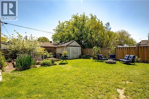 Expansive green lawn backyard featuring a wood storage shed, raised garden beds, and a full privacy fence - 364 Tragina Avenue N, Hamilton, ON - Outdoor With Backyard