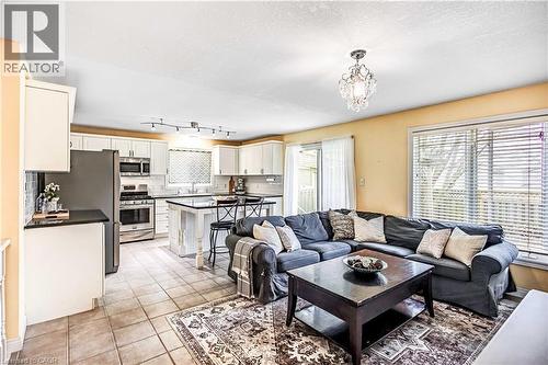 Living area featuring light tile patterned floors, hanging lights, and a textured ceiling - 65 Thistlemoor Drive, Caledonia, ON - Indoor Photo Showing Living Room